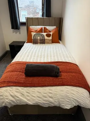 a bed with an orange and white blanket and pillows at 3BR Accommodation in St Helens - Sleeps 6 in Saint Helens