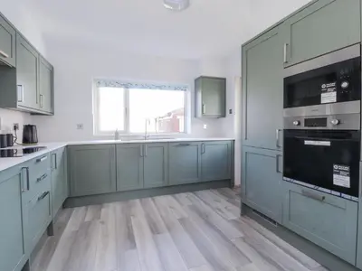 a large kitchen with blue cabinets and a window at 38 Clive Avenue in Lytham St Annes