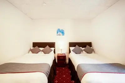 two twin beds in a room with a red carpet at HOTEL BLUE OCEAN - Call For Cheap Prices - Check In Until 3AM in Blackpool
