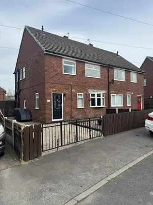 a brick house with a fence and a car parked in front at A spacious 3 bed semi-detached in Ince-in-Makerfield