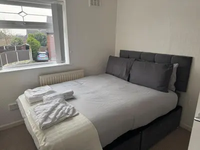 a bed in a room with a window at A spacious 3 bed semi-detached in Ince-in-Makerfield
