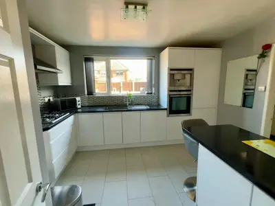 a kitchen with white cabinets and a black counter top at A spacious 3 bed semi-detached in Ince-in-Makerfield