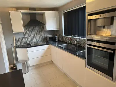 a kitchen with white cabinets and black appliances at A spacious 3 bed semi-detached in Ince-in-Makerfield