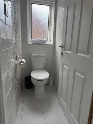 a white bathroom with a toilet and a window at A spacious 3 bed semi-detached in Ince-in-Makerfield