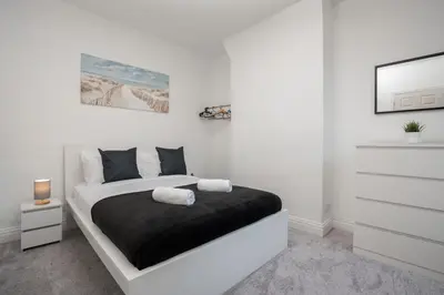 a white bedroom with a bed and a dresser at 5-Bedroom House Long Stays Contractors Liverpool Hinkley Homes in Liverpool