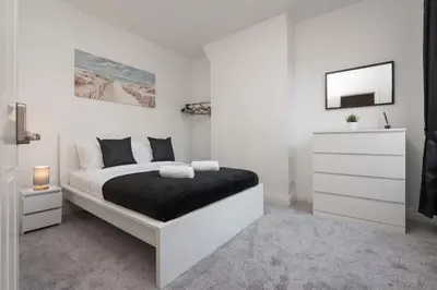 a white bedroom with a bed and a white dresser at 5-Bedroom House Long Stays Contractors Liverpool Hinkley Homes in Liverpool