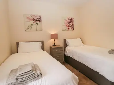 a bedroom with two beds and a lamp on a night stand at 7 Sandpiper in Carnforth