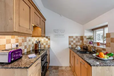 a kitchen with wooden cabinets and a plate of fruit on the counter at 2 Bed in Field Broughton oc-l31021 in Cartmel