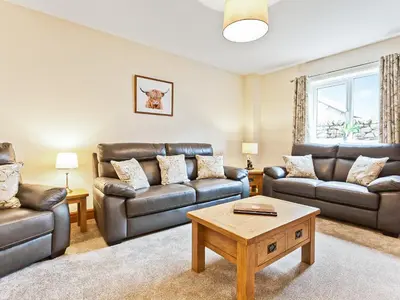 a living room with leather furniture and a coffee table at Tower Cottage in Arnside