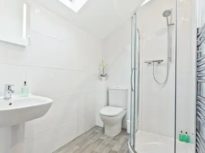 a white bathroom with a shower and a toilet at Tower Cottage in Arnside