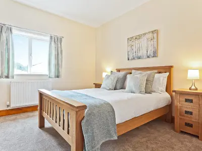 a bedroom with a large bed and a window at Tower Cottage in Arnside