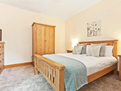 a bedroom with a bed and a wooden cabinet at Pier Cottage in Arnside