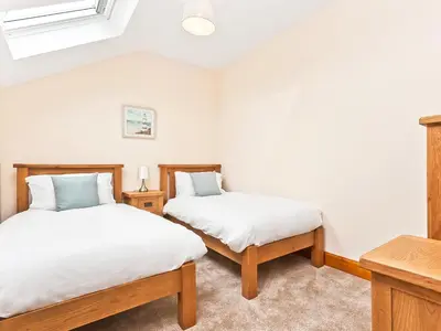 two twin beds in a room with white walls at Pier Cottage in Arnside
