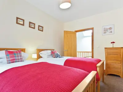 a bedroom with two beds and a window at Hollins Cottage in Silverdale