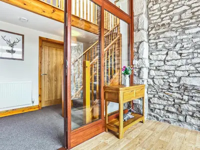a room with a wooden table and a stone wall at Hollins Cottage in Silverdale