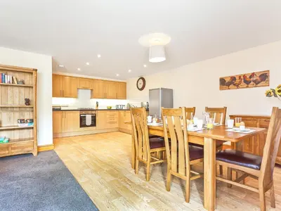a kitchen and dining room with a wooden table and chairs at Hollins Cottage in Silverdale
