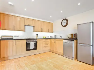 a kitchen with wooden cabinets and a clock on the wall at Hollins Cottage in Silverdale