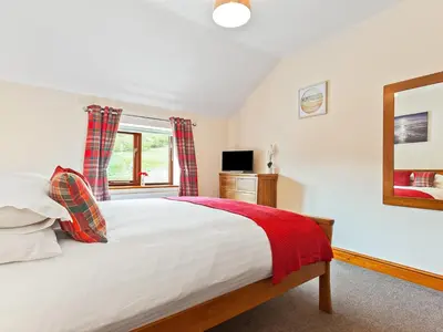 a bedroom with a bed and a mirror and a window at Hollins Cottage in Silverdale