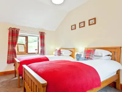 a bedroom with two beds and a window at Hollins Cottage in Silverdale