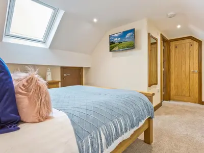 a bedroom with a blue bed and a window at Keer Cottage in Carnforth