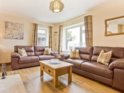 a living room with a brown leather couch and a table at Keer Cottage in Carnforth