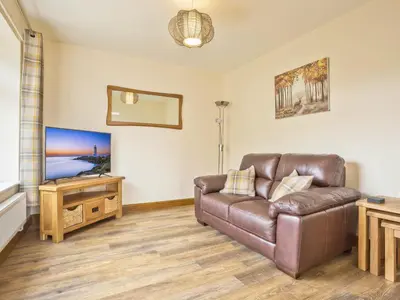 a living room with a leather couch and a television at Keer Cottage in Carnforth
