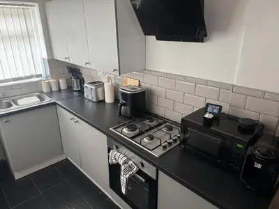 a small kitchen with a stove and a microwave at Knotty Ash - 3 Beds - Sleeps 6 - On-Site Parking in Liverpool