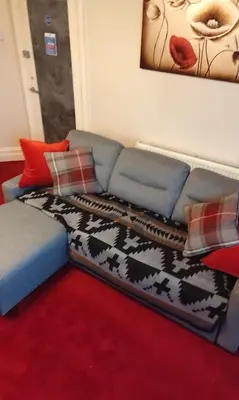 a living room with a blue couch with a blanket at Stratford House Holiday Apartments in Blackpool