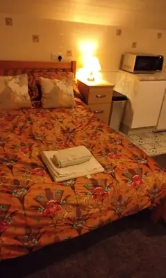 a bedroom with a bed with an orange blanket at Stratford House Holiday Apartments in Blackpool