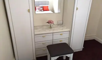 a dressing room with a mirror and a vase with a flower at Stratford House Holiday Apartments in Blackpool