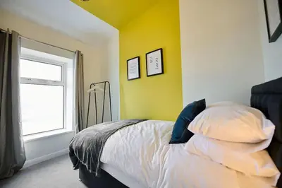 a bedroom with a bed with a yellow wall and a window at 2 Bedroom House- Contractors - Families - Sleeps 4 in Great Harwood