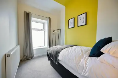 a bedroom with a bed with a yellow wall and a window at 2 Bedroom House- Contractors - Families - Sleeps 4 in Great Harwood