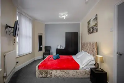 a bedroom with a red bed with a red blanket at The Ocean Inn in Blackpool
