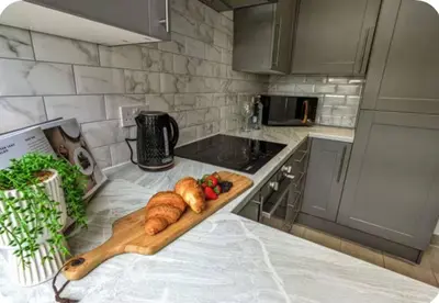 a kitchen with a cutting board and croissants on a counter at Spacious Bungalow in St Helens, 1-Min Drive to Carr Mill Bridge in Saint Helens