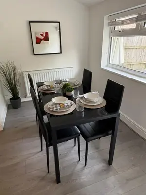 a dining room table with black chairs and a black table with plates andoverty at Spacious Bungalow in St Helens, 1-Min Drive to Carr Mill Bridge in Saint Helens