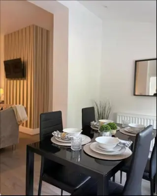 a black dining room table with black chairs with plates and bowls at Spacious Bungalow in St Helens, 1-Min Drive to Carr Mill Bridge in Saint Helens