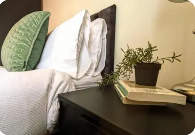 a bed with pillows and a table with a plant on it at Spacious Bungalow in St Helens, 1-Min Drive to Carr Mill Bridge in Saint Helens