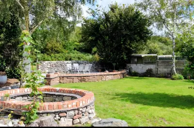 a garden with a retaining wall and a lawn at Foundry View in Millom