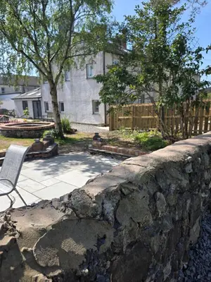 a stone retaining wall with a chair in a yard at Foundry View in Millom