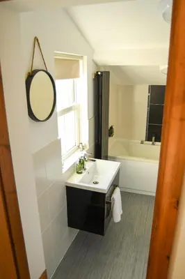 a bathroom with a sink and a tub and a mirror at Foundry View in Millom