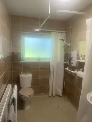 a bathroom with a toilet and a shower and a window at Seaview home in Baycliff, Cumbria in Baycliff