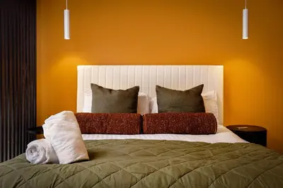 a bedroom with a large bed with an orange wall at Stylish 4-Bed House Central Blackpool Family Stay in Blackpool