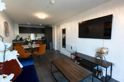a living room with a table and a television on a wall at Stylish Luxury Penthouse in Liverpool City Centre - Free Private Parking and Only 2km from Everton Stadium! in Liverpool