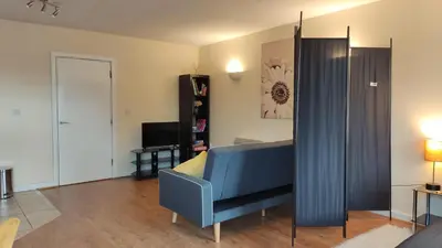 a living room with a blue couch and a television at Modern Studio Flat in Wigan in Wigan