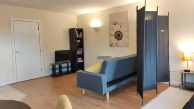 a living room with a blue couch and a television at Modern Studio Flat in Wigan in Wigan