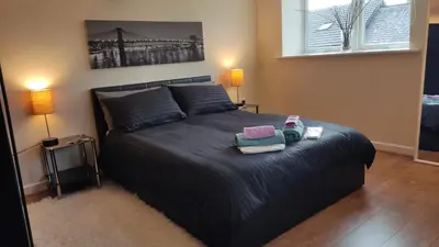 a bedroom with a black bed with two lamps at Modern Studio Flat in Wigan in Wigan