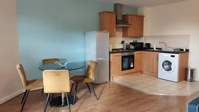 a kitchen with a table and a washer and dryer at Modern Studio Flat in Wigan in Wigan