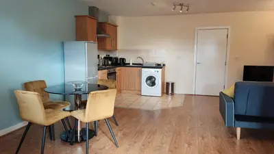 a kitchen and living room with a table and chairs at Modern Studio Flat in Wigan in Wigan