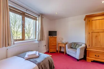 a bedroom with a bed and a chair and a window at 2 Bed in Carnforth oc-s31763 in Warton