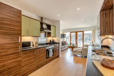 a kitchen with wooden cabinets and a living room at 2 Bed in Carnforth oc-s31763 in Warton